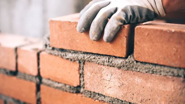 Hand placing brick on wall